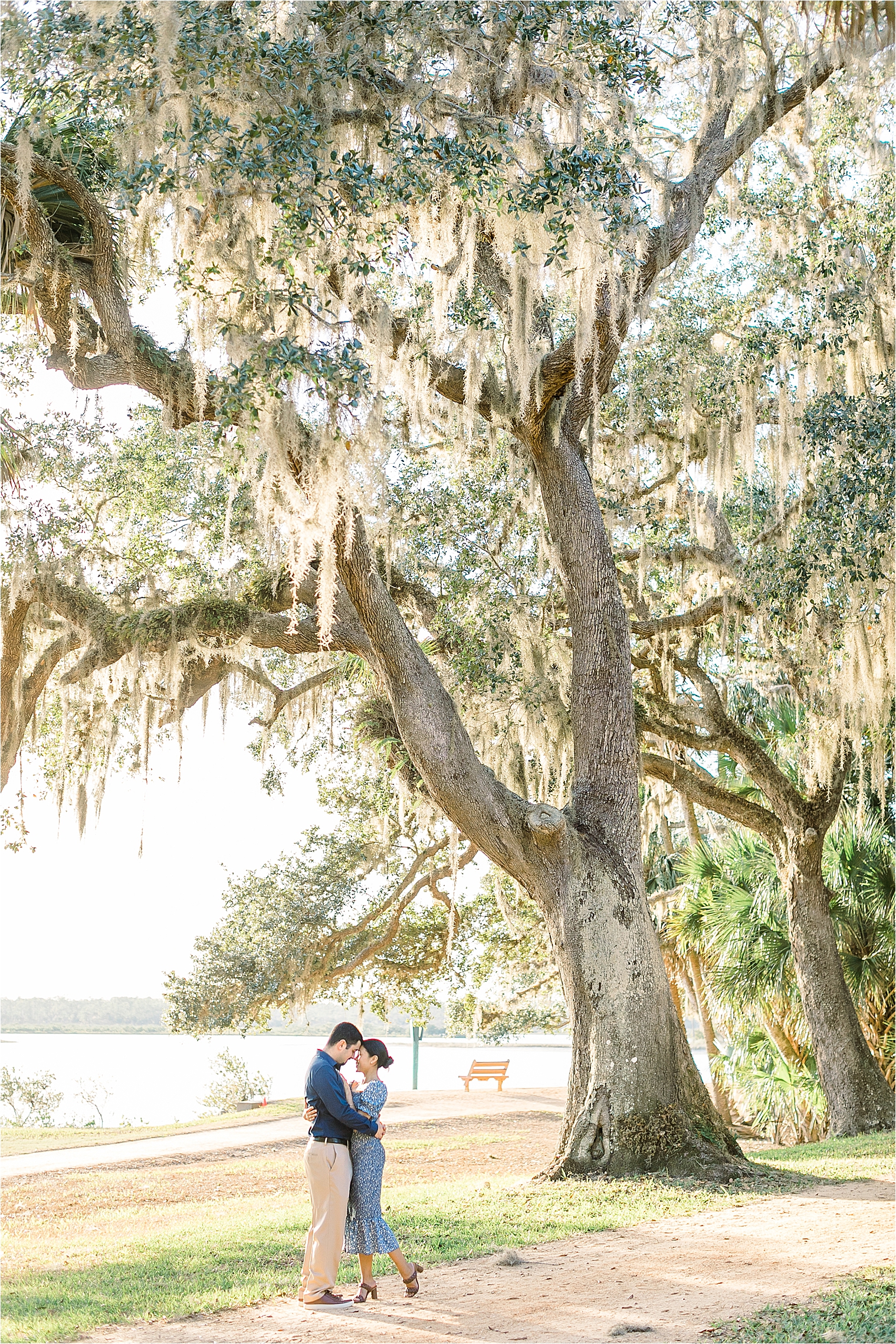 couple standing under oak trees with moss